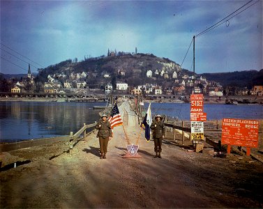 C-888 - Pfc. Vernon H. Bradberry, Abbesville, S.C., left, Pfc. Robert L. Mims, Laurence, S.C., of the M.P. Company stand in front of the heavy pontoon bridge linking Remagen and Linz, across the Rhine.