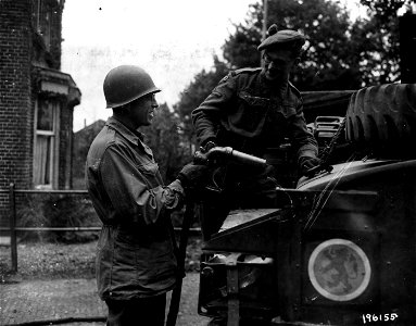 SC 196155 - US Army Pvt. Harry U. Cremer of Minonk, Ill., American 7th Arm'd. Div., helps a British soldier, Lance Bombardier Harry Frost of London, England, British Scottish 16th Div., at Someren, Holland.