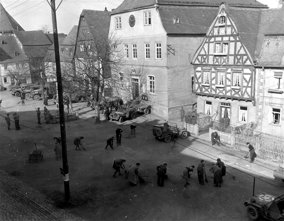 SC 335276 - German men and women sweep up street in front of command post of 11th Armored Division, 3rd U.S. Army, in Kirchberg, Germany. 20 March, 1945.
