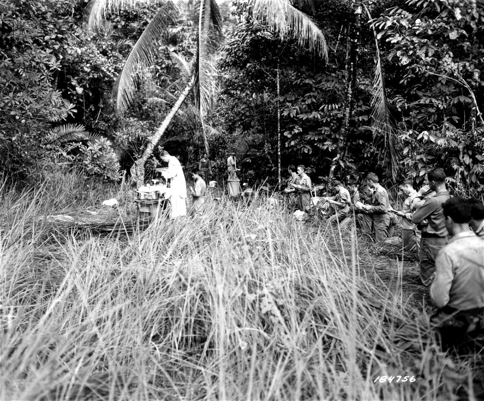 SC 184756 - Chaplain Owen Monahan of 41st Div. Artillery holding services at newly-captured village in New Guinea, for men not actively involved in the battle 300 yards ahead. 25 July, 1943. photo