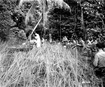 SC 184756 - Chaplain Owen Monahan of 41st Div. Artillery holding services at newly-captured village in New Guinea, for men not actively involved in the battle 300 yards ahead. 25 July, 1943.