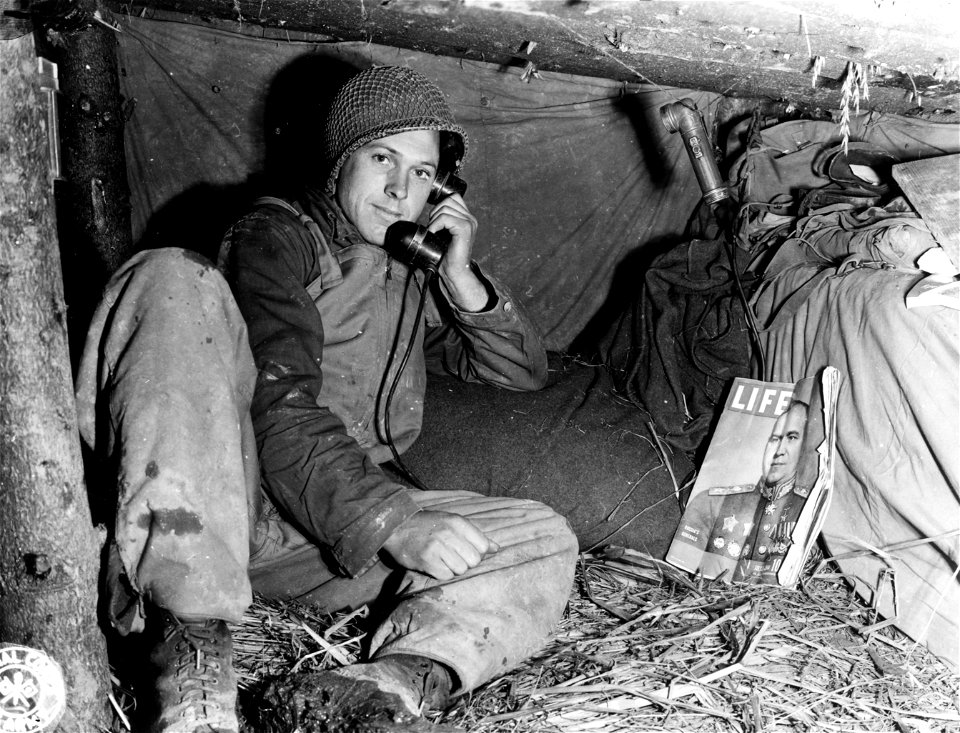 SC 195686 - Sgt. Hubert E. Bankston, Jasper, Ala., reclines inside his deluxe foxhole which boasts sleeping quarters for two men and a roof of 6 inch logs with three feet of mud covering it. 17 October, 1944.