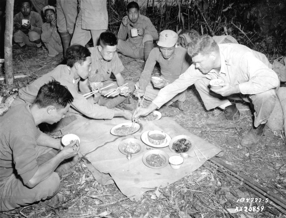 SC 184777-S - Maj. Graham Batchelor, Milledgeville, Ga., U.S. Army Infantry Liaison Officer, uses chop sticks and a Chinese mess bowl while eating with Chinese officers of an American-trained Chinese division in the China, Burma, India Theater.