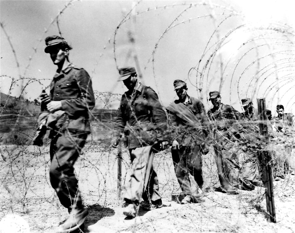 SC 329876 - Prisoners of war file into a II Corps enclosure. 18 April, 1945.