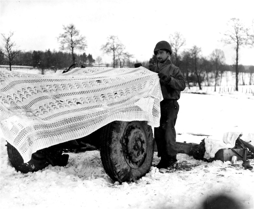 SC 199100 - Pvt. Joseph M. Belle, Route 55, Rome, N.Y., of the 75th Infantry Division uses a white lace cloth to camouflage three-inch gun in a snow-covered field in Belgium.