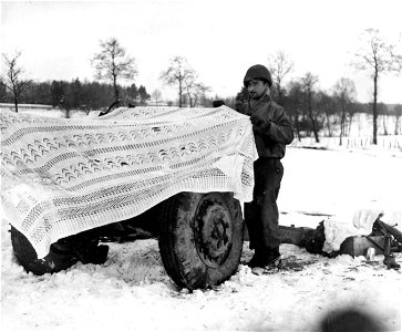SC 199100 - Pvt. Joseph M. Belle, Route 55, Rome, N.Y., of the 75th Infantry Division uses a white lace cloth to camouflage three-inch gun in a snow-covered field in Belgium. photo