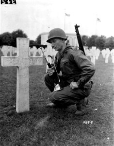 SC 195515 - Warrent Officer Marcus L. Reik kneels before the grave of the first soldier to be buried in the St. Mihiel American Cemetary during World War I.