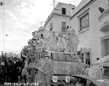 SC 171639 - Tunis civilians give the "V" sign as American soldiers come into the town in G.I. trucks.