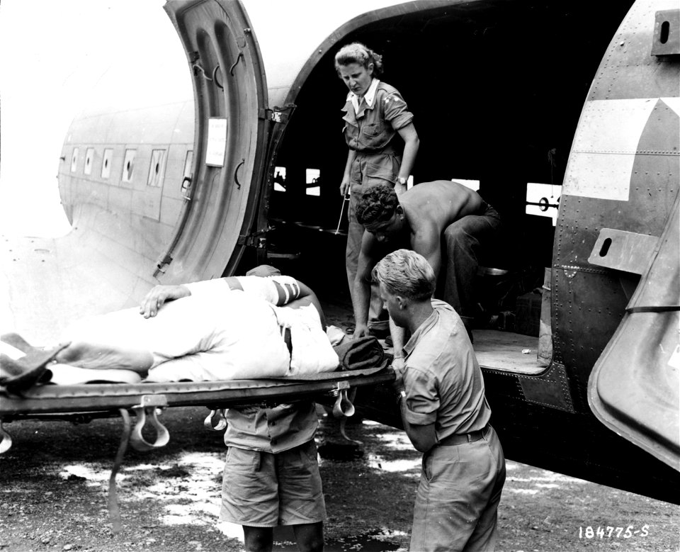 SC 184775-S - Lt. Rial Smith, Jersey Shore, Pa., Air Evacuation Nurse, watches carefully while a soldier wounded in the fighting on Bougainville Island in the Solomons is unloaded from a plane...