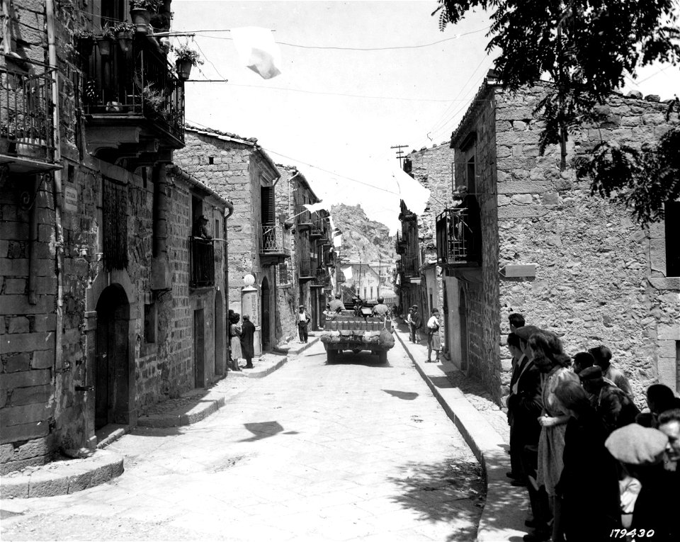 SC 179430 - Soldiers looking for snipers in the city of Mistretta, captured by 1st U.S. Inf. Div. White flags are displayed by civilians. 30 July, 1943.