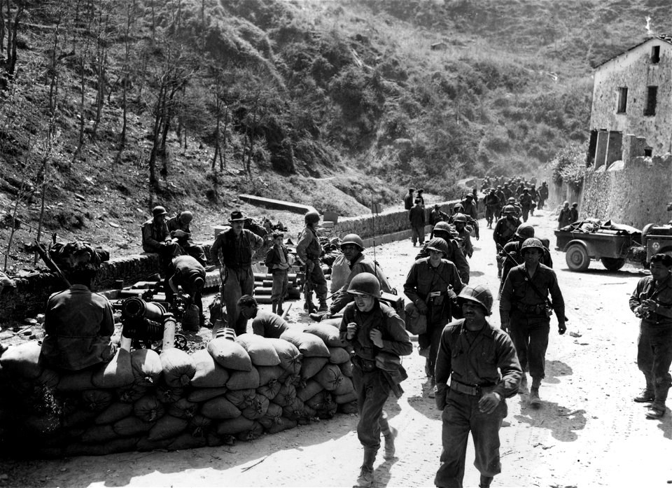 SC 337157 - Men of 2nd Bn., 370th Inf. Regt., move through Prato, past 75mm howitzer of Cannon Co., 442nd Regt. 9 April, 1945.