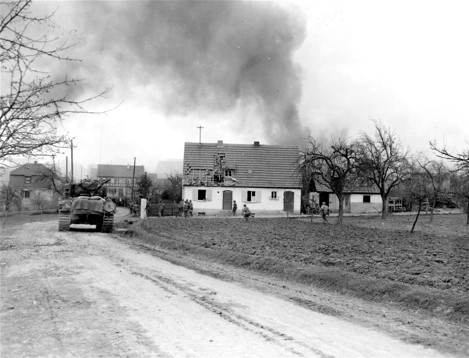 SC 336917 - Tanks and armored infantrymen enter burning town of Wasserlossen against enemy small arms fire, to wipe out the remaining pockets of enemy resistance after pre-attack shelling set town afire and knocked out anti-tank guns.