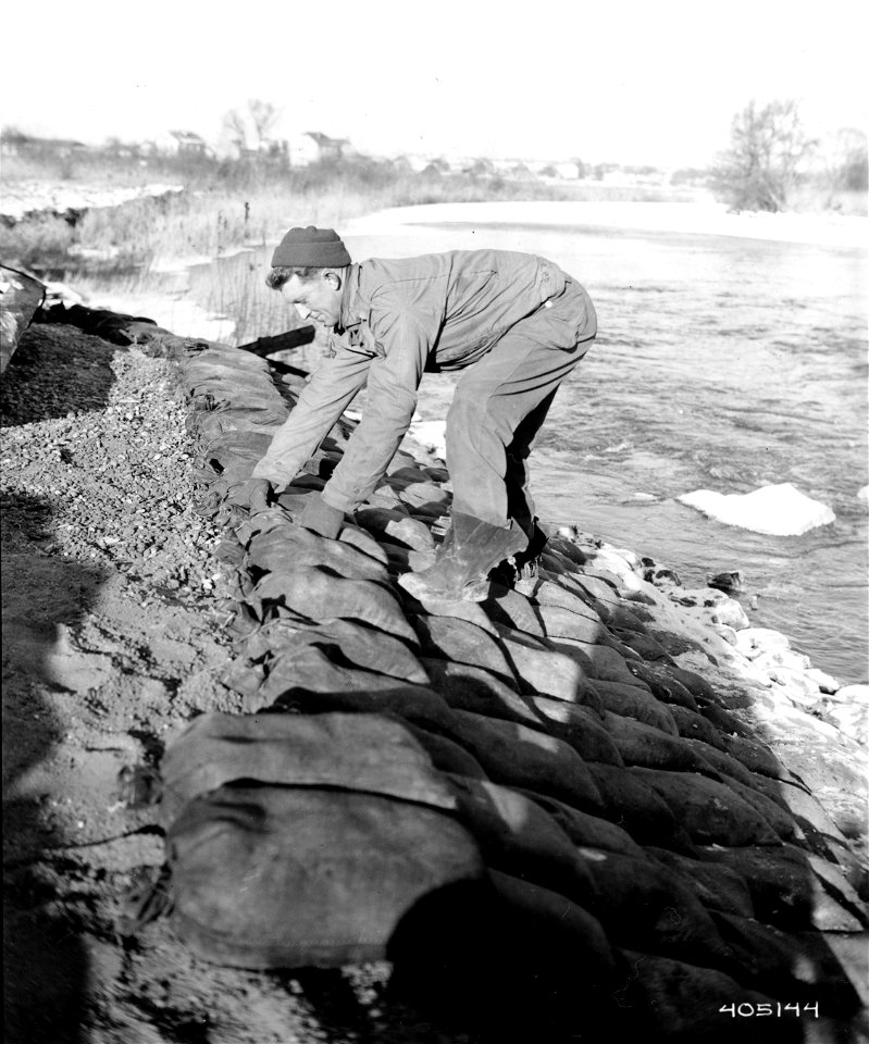 SC 405144 - Cpl. William C. Bruton, Graham, Texas, 347th Engineer Regiment, places sand bags with cement around to support a reconstructed railroad pier and to secure it from being smashed out.