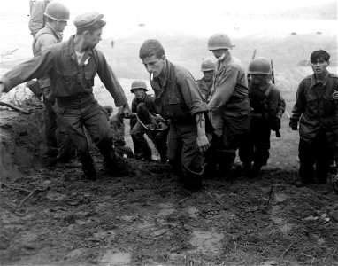 SC 348676 - Men of the 21st Inf. Regt., 24th Inf. Div., carry a wounded soldier from the battle line on the Naktong River in Korea. 19 September, 1950.