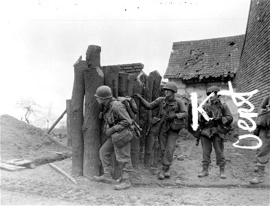 SC 374766 - Infantrymen of 104th Division, 1st U.S. Army, shelter by road block in shell-torn Manheim, Germany. Town is under German artillery attack. 27 February, 1945.