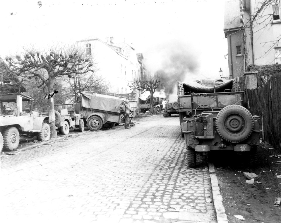 SC 335263 - Black smoke pours from blazing tank loaded with ammunition, in background, which was set afire by German bombardment in Linz, Germany, on the east bank of the Rhine River.