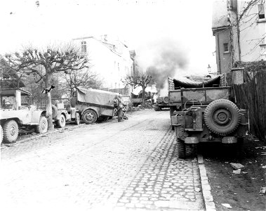 SC 335263 - Black smoke pours from blazing tank loaded with ammunition, in background, which was set afire by German bombardment in Linz, Germany, on the east bank of the Rhine River.