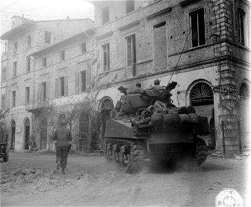 SC 337149 - Tank spins around a corner, and the sign on the building points toward Massa. 8 April, 1945.
