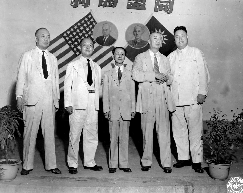 SC 334926 - High Chinese officials, attending War Transportation Board dinner at Chungking in victory celebration, stand in front of crossed flags of two nations and pictures of Truman and Chiang Kai-Shek.