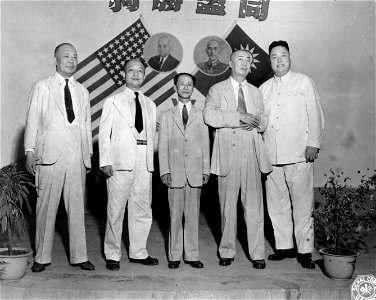 SC 334926 - High Chinese officials, attending War Transportation Board dinner at Chungking in victory celebration, stand in front of crossed flags of two nations and pictures of Truman and Chiang Kai-Shek.