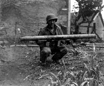 SC 195516 - Pfc. Fred A. Burns, 4405 Sullivan Avenue, St. Bernard, Ohio, of the 36th Division, is shown with a German "bazooka" which he captured during fighting in a town in France, along with five Germans. photo