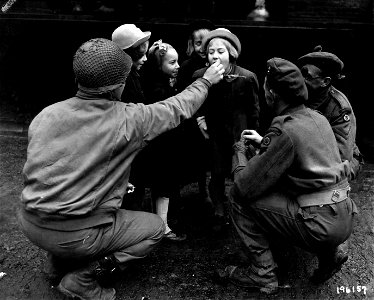 SC 196157 - American 7th Armd. Div., and British 15th Scottish Div. troops fighting, working and playing together, combine operations and give sweets to small Dutch Children, in [illegible], Holland.