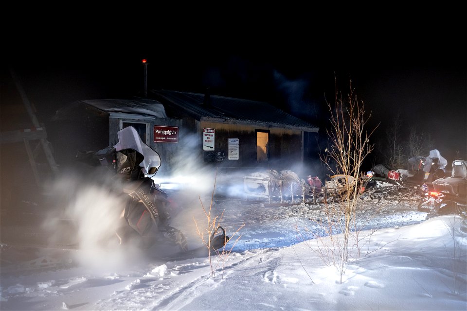 Snowmachines and sleds at night
