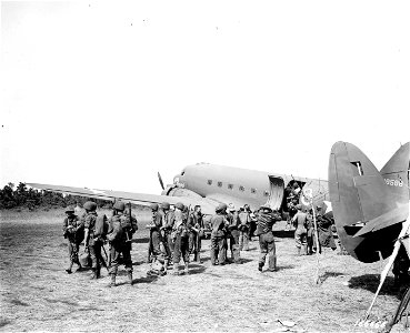 SC 166665 - On alighting from a transport plane, soldiers adjust clothing and equipment. 15 December, 1942.