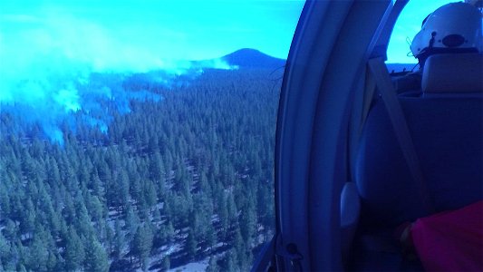 Crew Member Surveys Smokey Forest from a Helicopter