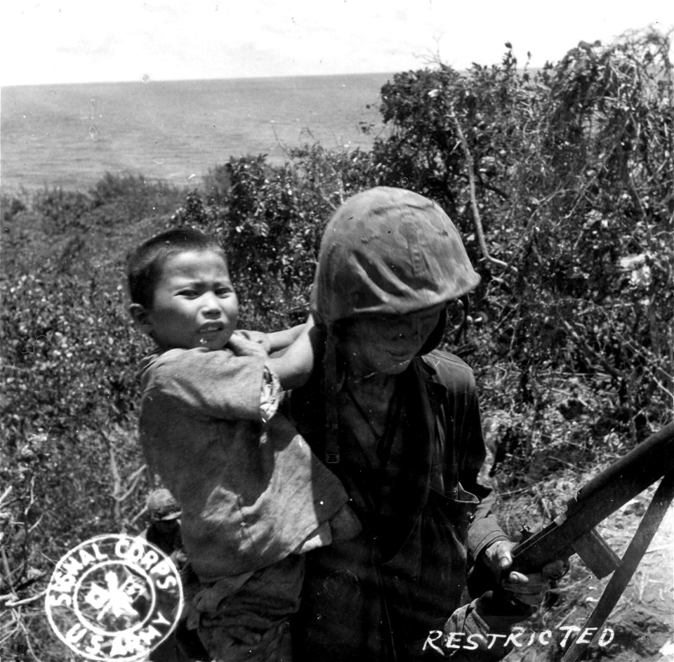 SC 405012 - A Marine carries a Japanese boy out of a cave, after he was forced to shoot the boy's father who chose to fight rather than surrender.