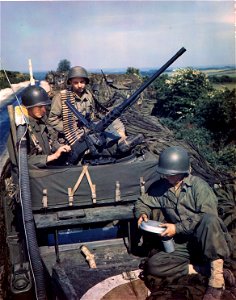 C-1081 - Three soldiers on top of a halftrack make last minute check on their guns and equipment prior to boarding a ship for the invasion. photo