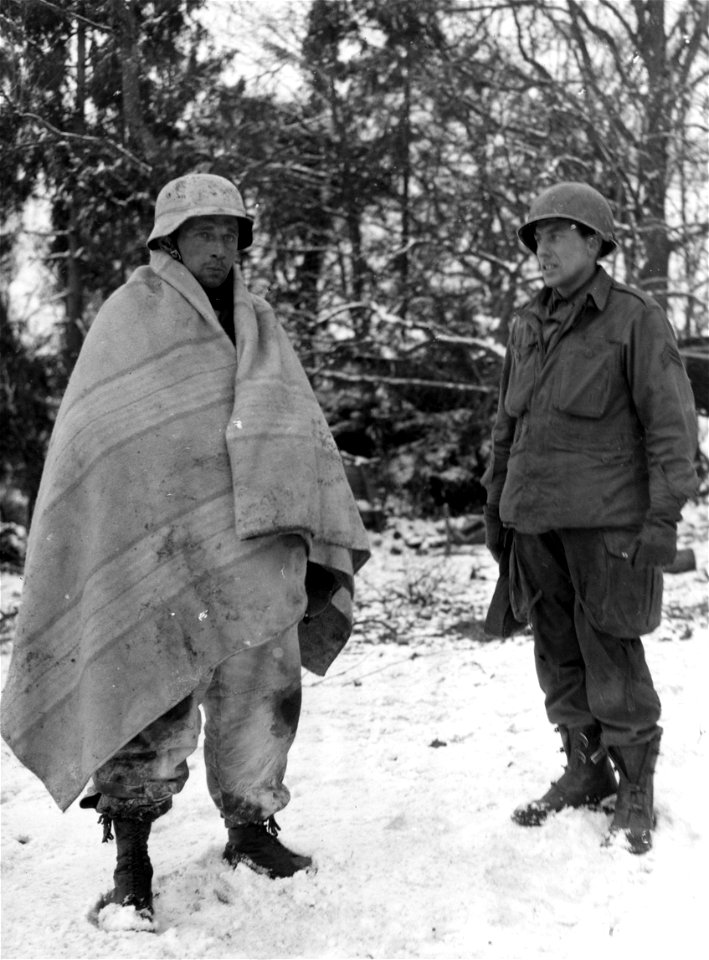 SC 198883 - Sgt. Charles J. Ten Barges, Haubstadt, Ind., guards a captured Nazi sergeant SS trooper who is wearing a light-colored blanket to camouflage him from the snow.