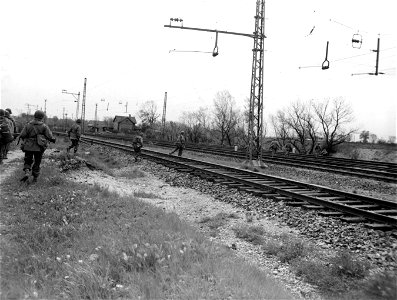 SC 270656 - These infantrymen spread out, giving the enemy a poor target as they cross the electric railway line on the outskirts of Munich. 30 April, 1945.