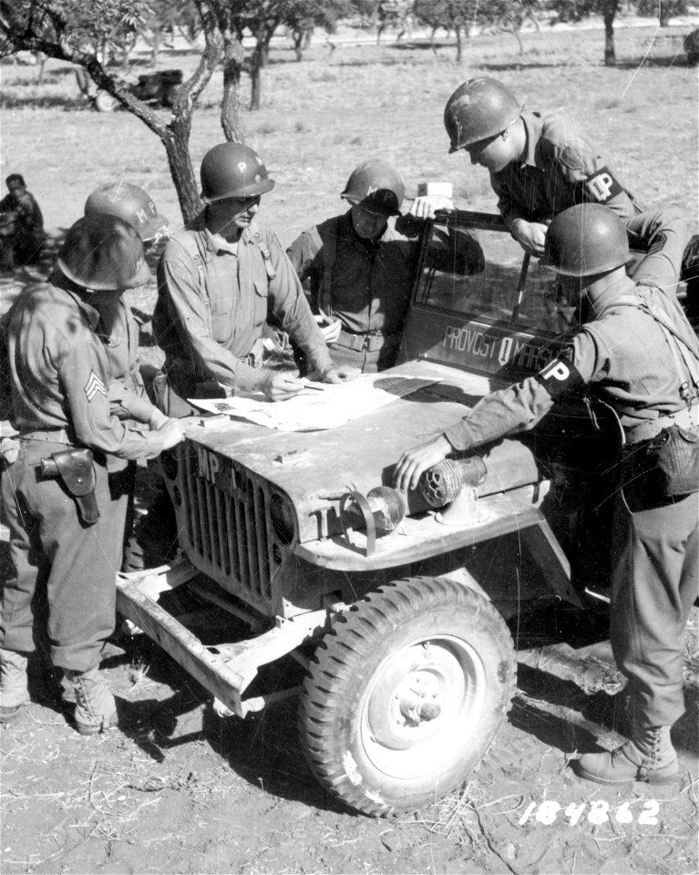 SC 184862 - 1st Division Military Police, near front lines on Sicily, get map directions from from Major Thomas Lanser, New York, 1st Division Provost Marshal, before going up to their posts at the frontline. 19 July, 1943.