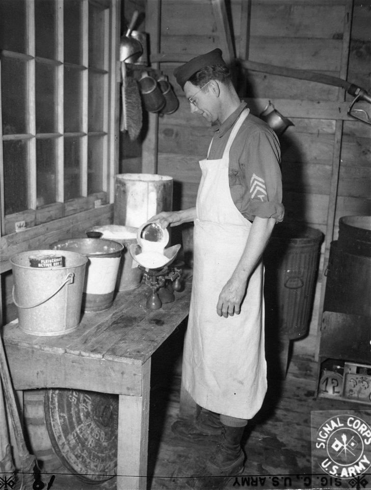 SC 405107 - The first step in the making of a batch of bread, the weighing out of the ingredients, is done by T/4 Clarence Benson of the 272nd QM Bakery on Kiska. 14 January, 1944.