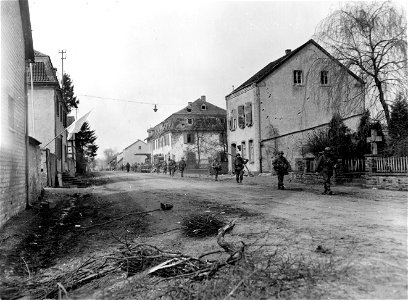 SC 336809 - Infantrymen of the 1st Division, 1st U.S. Army, move through the streets of Uckerath, Germany, on their way to the front. 25 March, 1945.