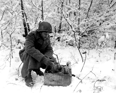 SC 396849 - Pvt. Joy B. Richcreek, North Fortville, Indiana, cooking his dinner over a lit can of gasoline in the snow-covered woods. Belgium. 4 January, 1945. photo