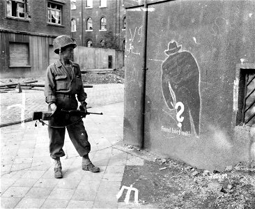 SC 195639 - Pfc. Hoyle E. Lougherty, Knoxville, Tenn., looks at a warning sign posted by the Nazis for the German citizenry of Aachen, Germany. photo