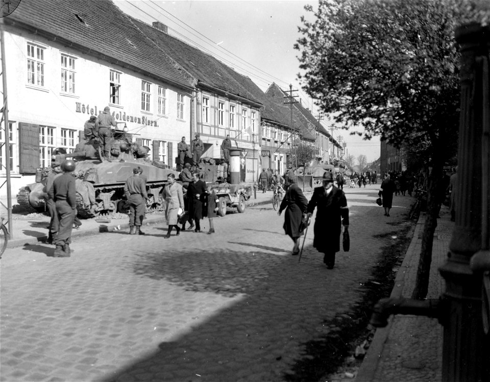 SC 336823 - Street scene in Seehausen, Germany, shows elements of a tank battalion, 5th Armored Division, 9th U.S. Army, and civilians eager to get to the stores before curfew. 16 April, 1945.
