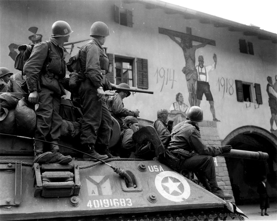 SC 374710 - Infantrymen on tanks [sic] in city square of Berchtesgaden looking at large painting on wall of building in in the square in memory of World War I.