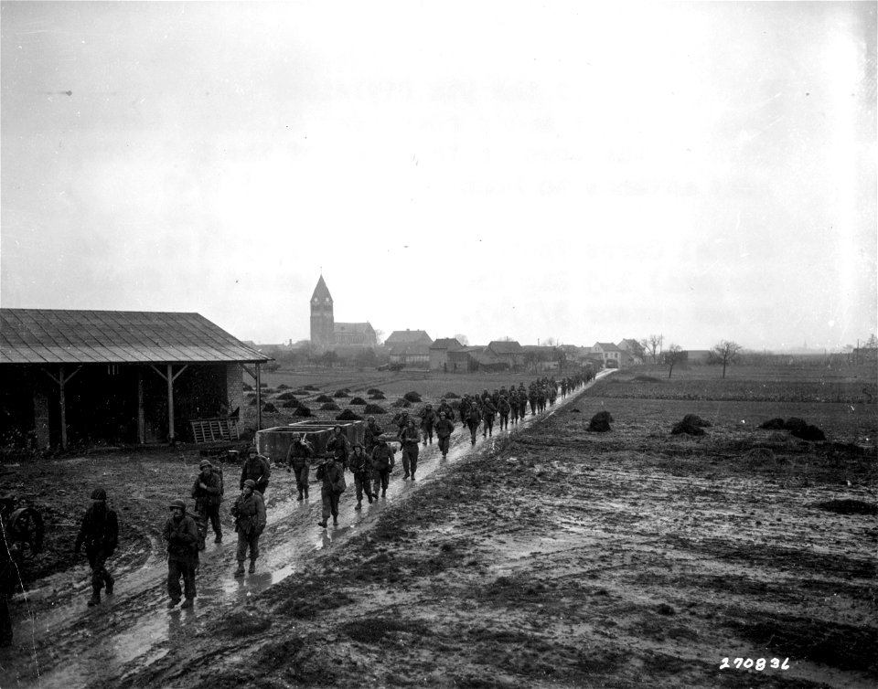 SC 270836 - Infantrymen of the 9th Division, U.S. First Army, march along a muddy road near Ollheim, Germany.