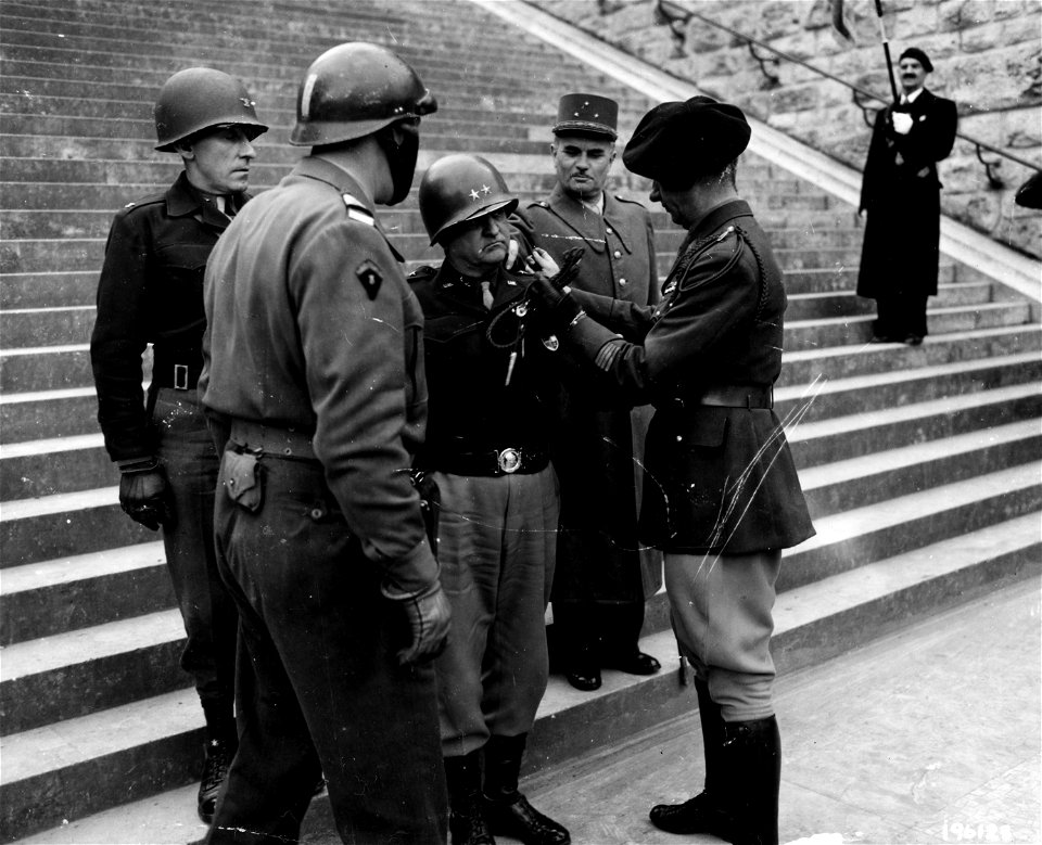 SC 196123 - Maj. Gen. Walton H. Walker, Commanding general 20th Corps, 3rd Army, is presented with the French Fouragere (Fourragère) by Major Paul Aubrey, commanding officer of the regular French Army, somewhere in France.