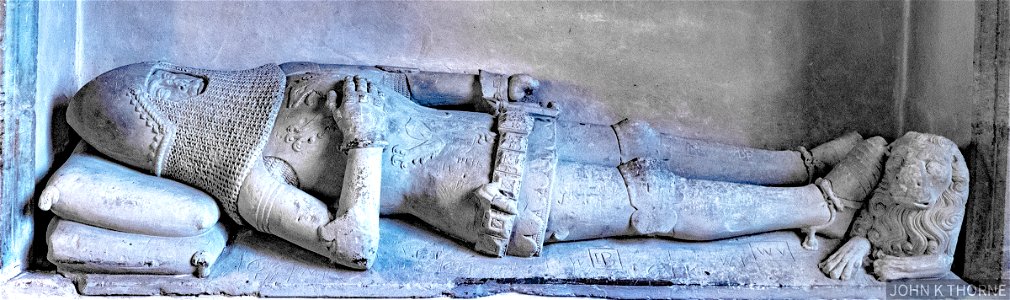 Sir Thomas Cawne, d.1374. Well preserved figure of reclining knight in plate armour and mail, under cusped and sub-cusped arch with square hood