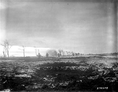 SC 270604 - American troops of the 8th(?) Regiment, 2nd Infantry Division, move across a field near Schoneseiffen, Germany, as enemy shell bursts in foreground. 2 February, 1945. photo