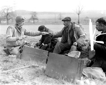 SC 405025 - Lt. Arnold Samuelson, Tacoma, Washington, Combat Photographic Officer attached to the 1st U.S. Army, gives food to hungry Russian slave laborers, who were liberated when elements of the 9th Armored Division took Limburg, Germany. photo