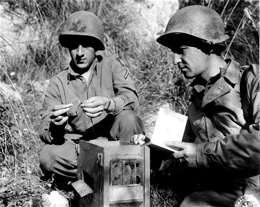 SC 184726 - Pvt. Frank M. Mis, Beacon Falls, Conn., at 45th Div. Command Post, takes instruction on attaching capsule containing message to pigeon's leg from Pfc. John A. Oeverso, Solvay, New York, serving with 6681 Signal Pigeon Company. photo