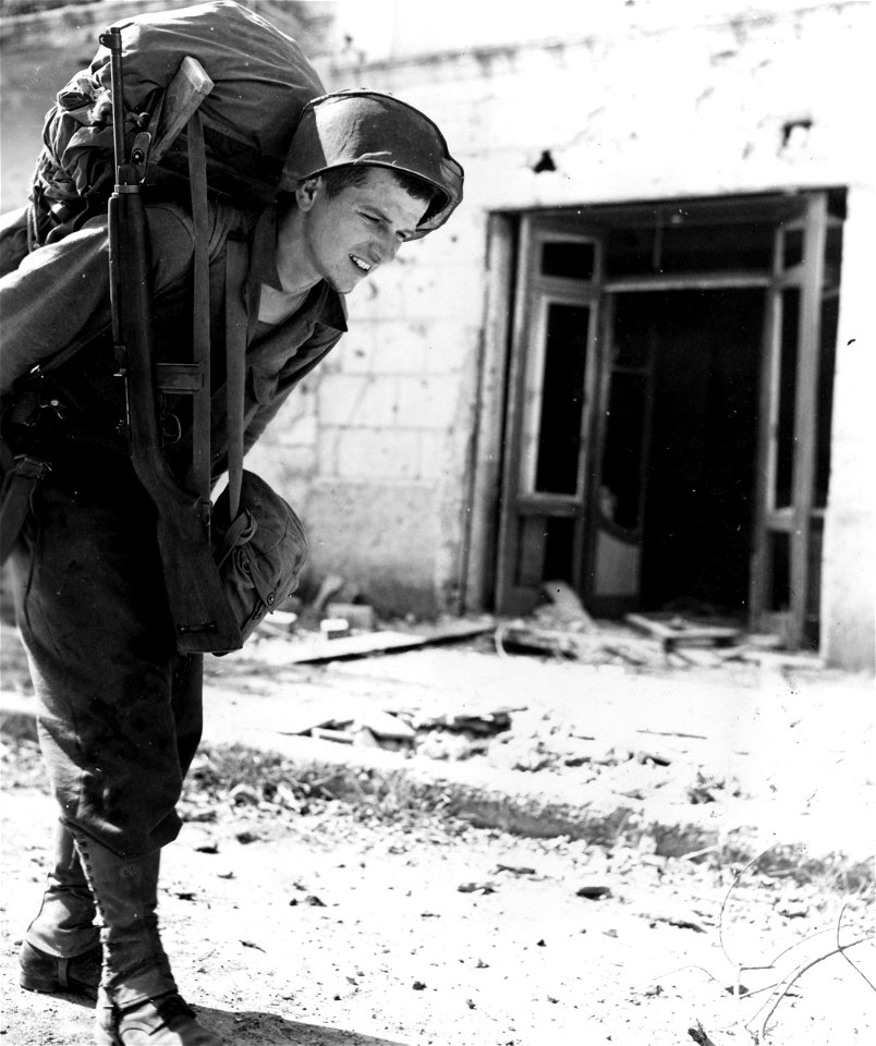 SC 374748 - Pvt. Joseph A. Zbin, Cleveland, Ohio, of Co. A, 338th Inf. carrying a 90 lb load of mortar ammo through town of Scauri. 16 May, 1944.