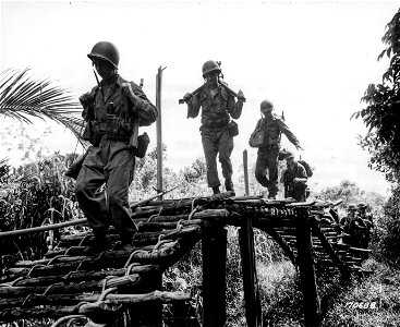 SC 170688 - Men of a Cannon Co. crossing Eroro Creek, New Guinea, on their way to Embogu, which is about four miles from Eroro Mission. 14 November, 1942.