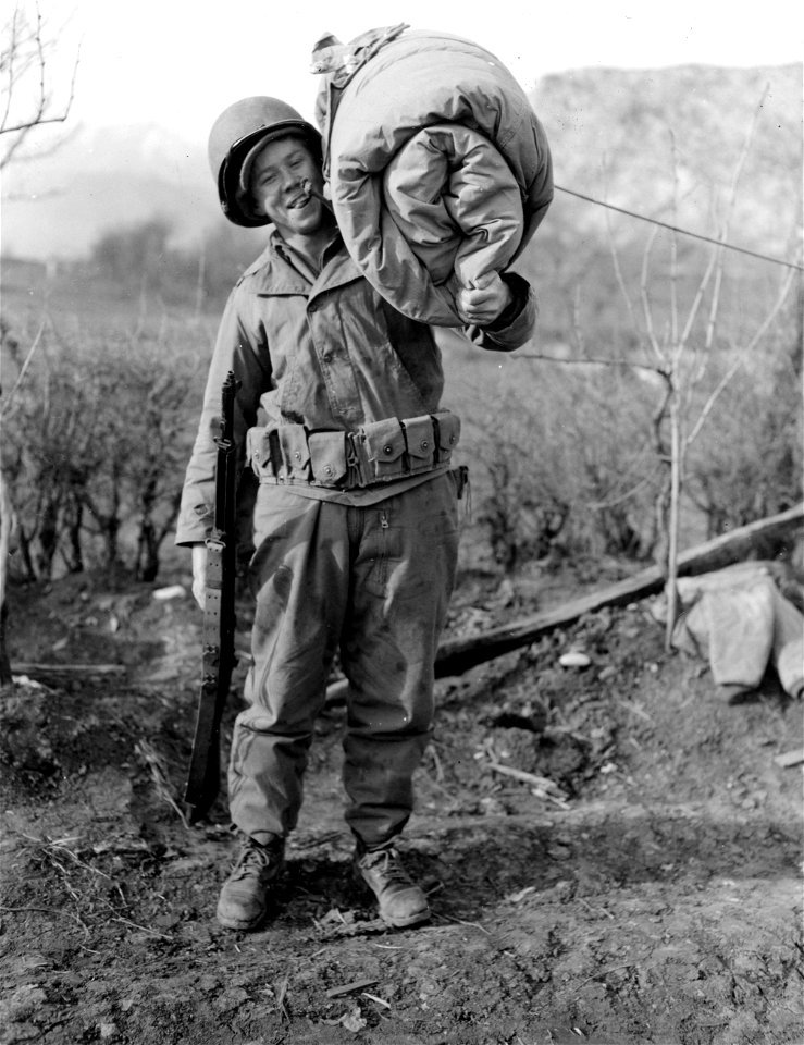 SC 374757 - It's a load for 98 lb. Pfc. Colon F. Price, Great Falls, S. Car., but he's glad to leave after 23 days up front under enemy observation. His outfit will leave under cover of darkness, just as they took up their position.