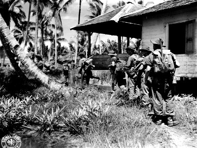SC 374826 - Patrols of 29 Bn., 18th Brigade move cautiously into the village area of Penadjam, Balikpapen, Borneo, under sniper fire. 5 July, 1945. photo